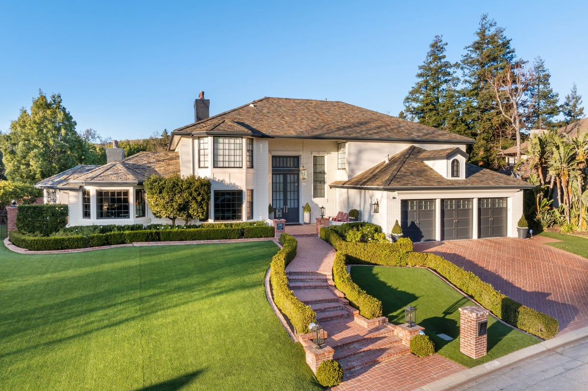 A brick driveway and entrance area of an estate with manicured landscaping