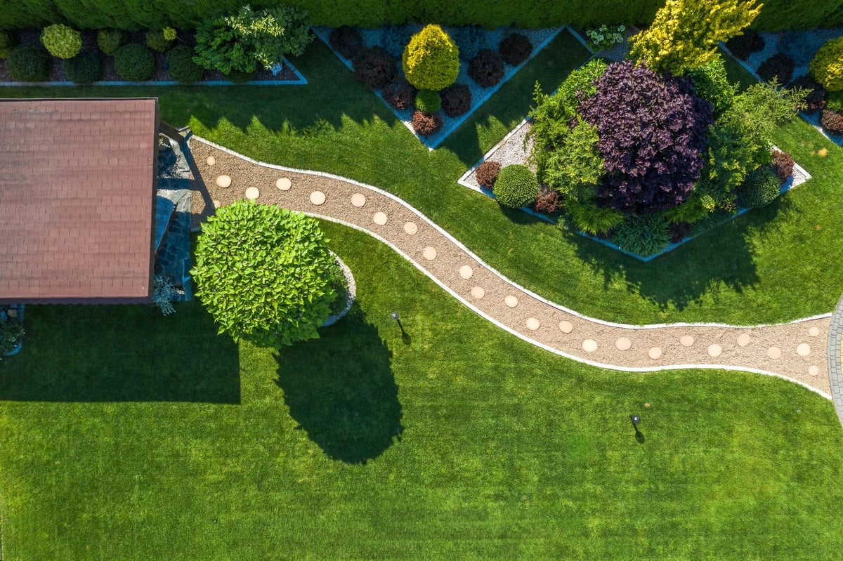 Aerial view of a vibrant garden with a winding stone path and manicured grass